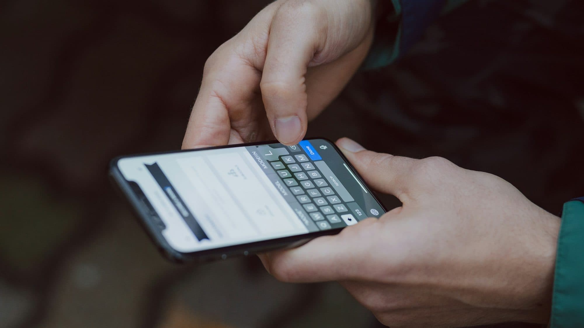 Two hands typing carefully on a smartphone